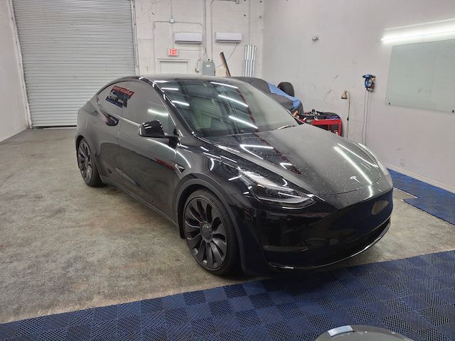 A black tesla model y is parked in a garage.