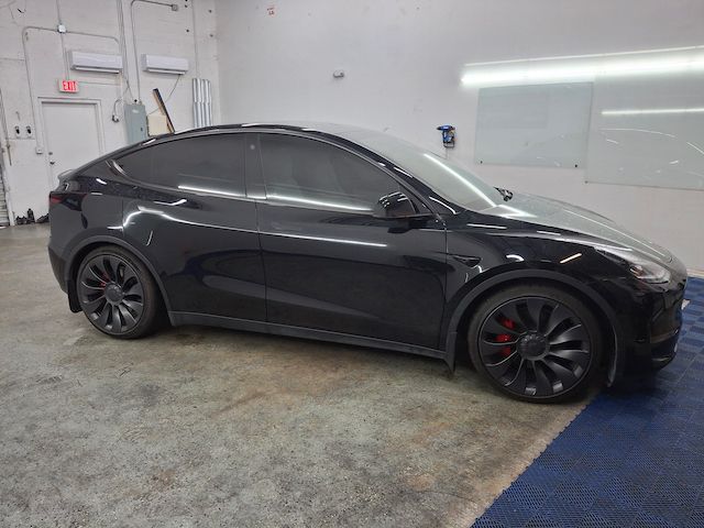 A black tesla model y is parked in a garage.
