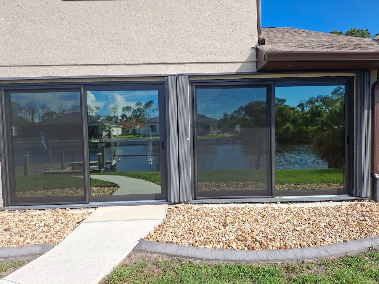A house with sliding glass doors has a walkway leading to it