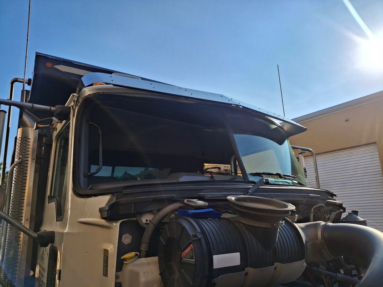 A truck with a broken windshield is parked in front of a building.