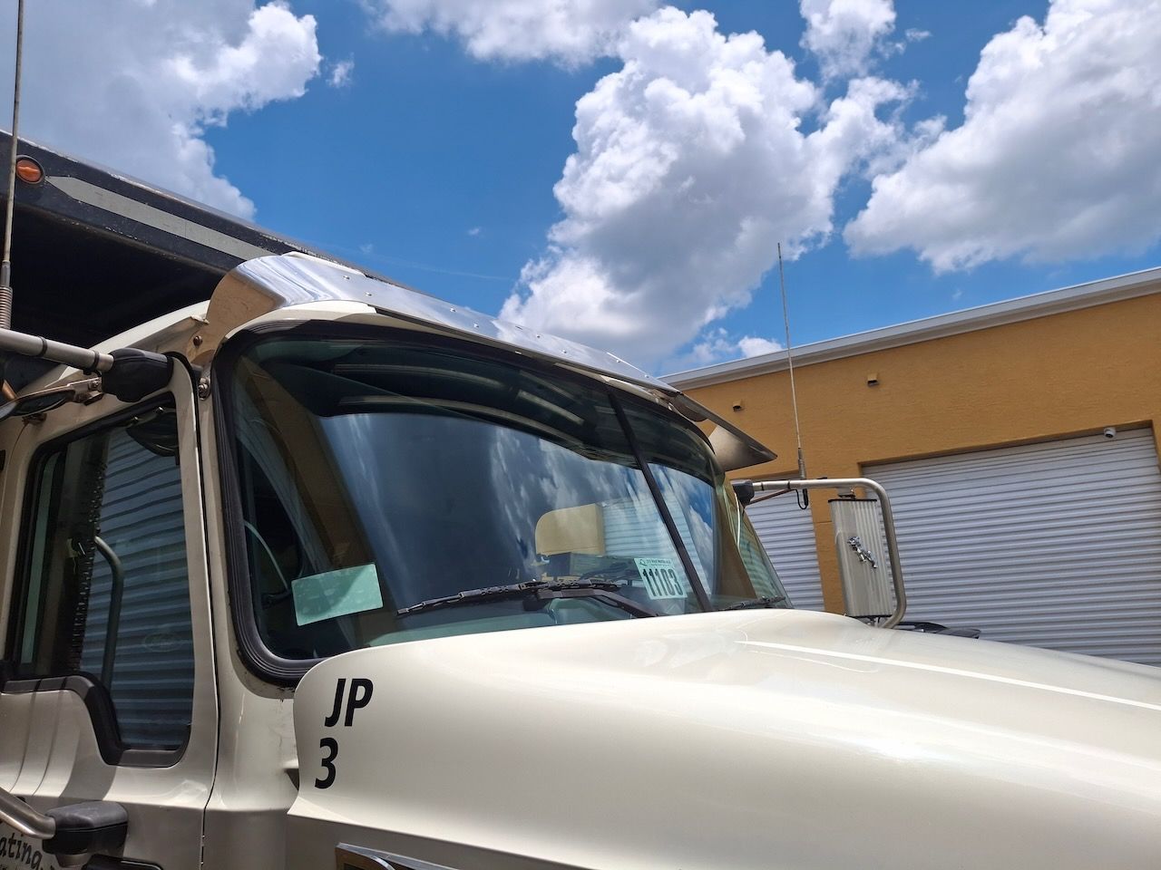 A white truck with the number 3 on the front is parked in front of a building.
