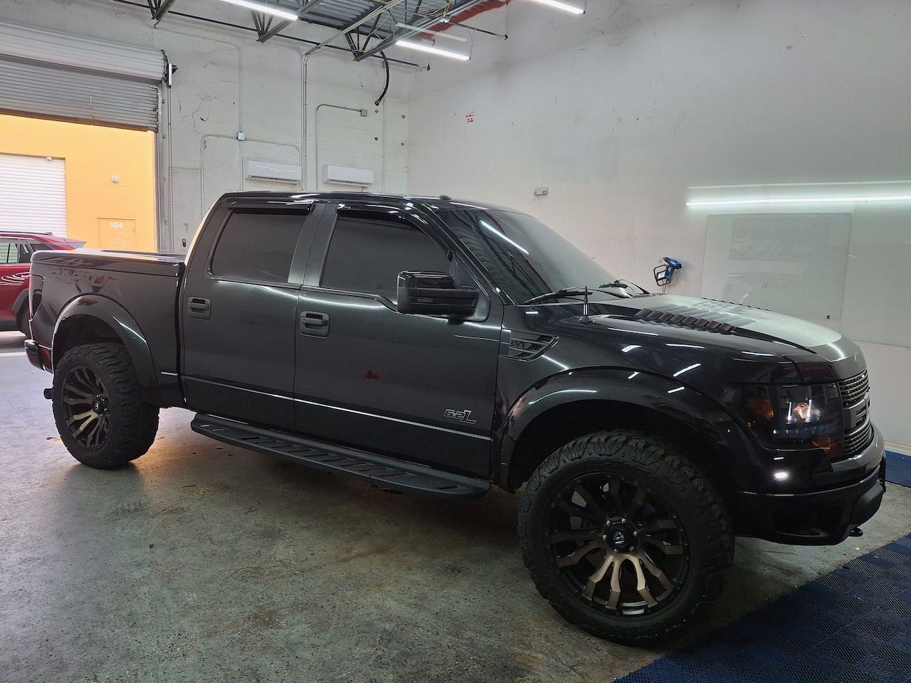 A black pickup truck is parked in a garage.