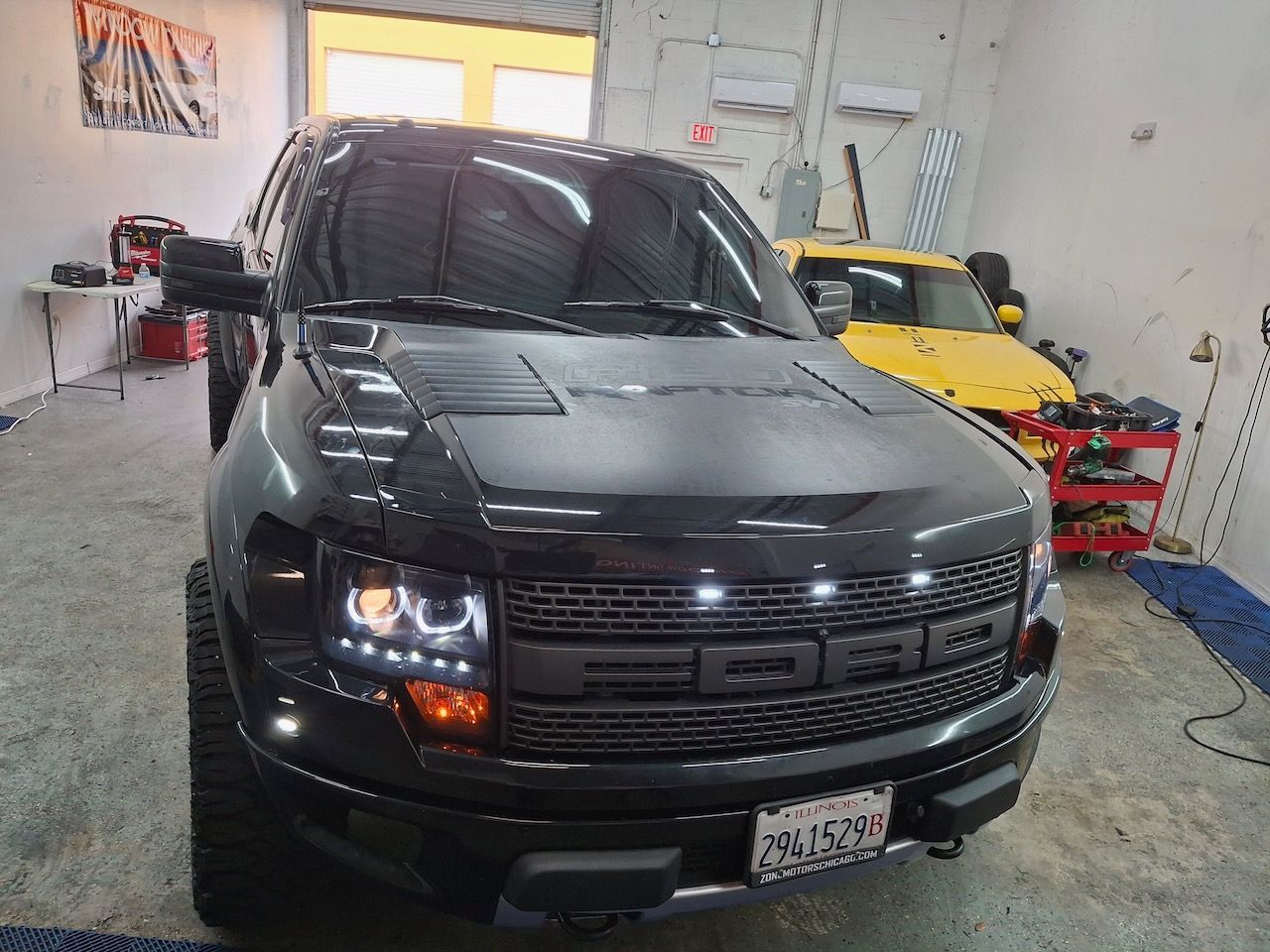 A black ford raptor is parked in a garage.