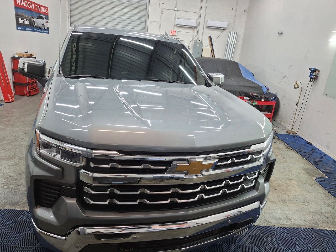 A gray chevrolet silverado is parked in a garage.