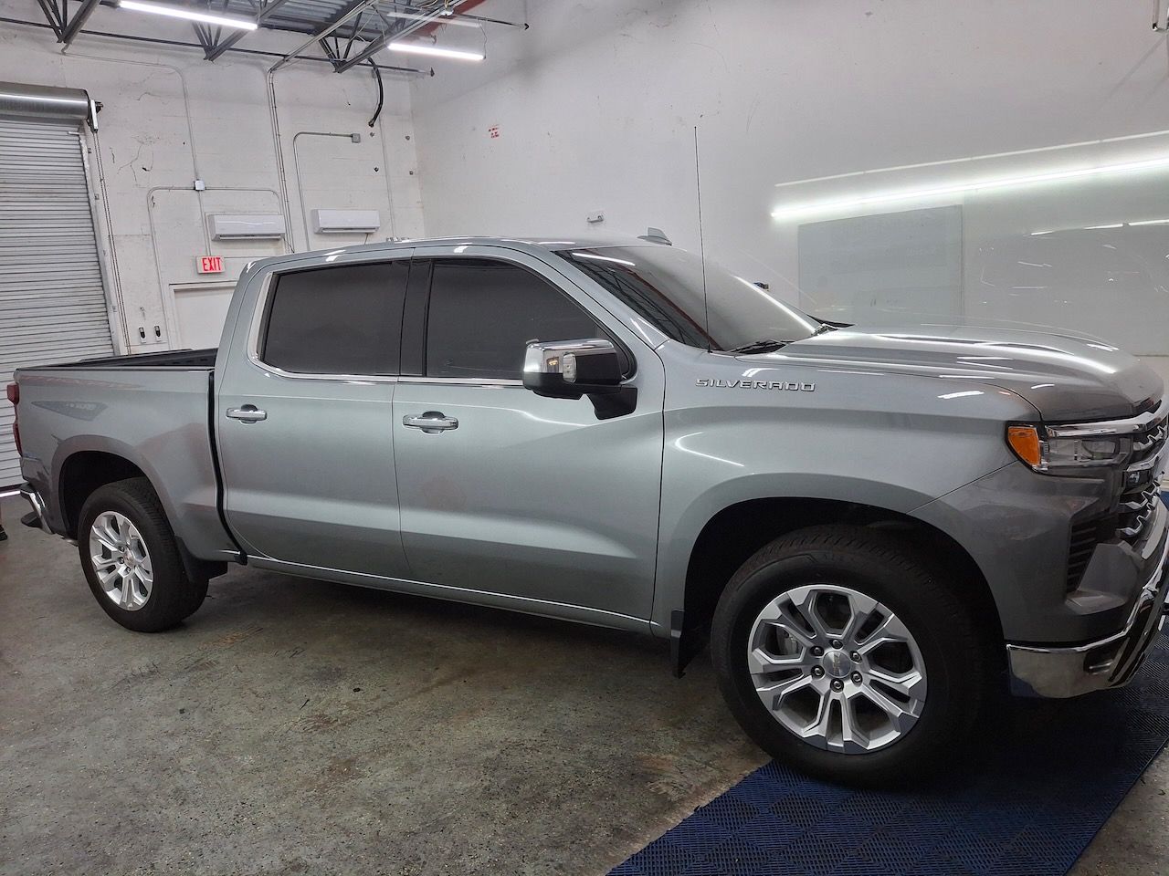 A silver pickup truck is parked in a garage.