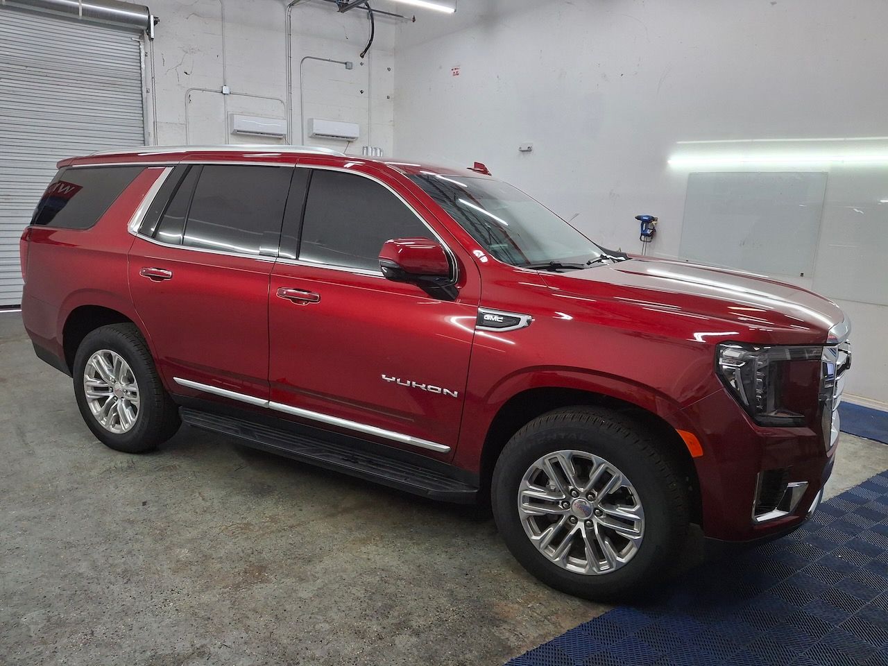 A red gmc yukon is parked in a garage.