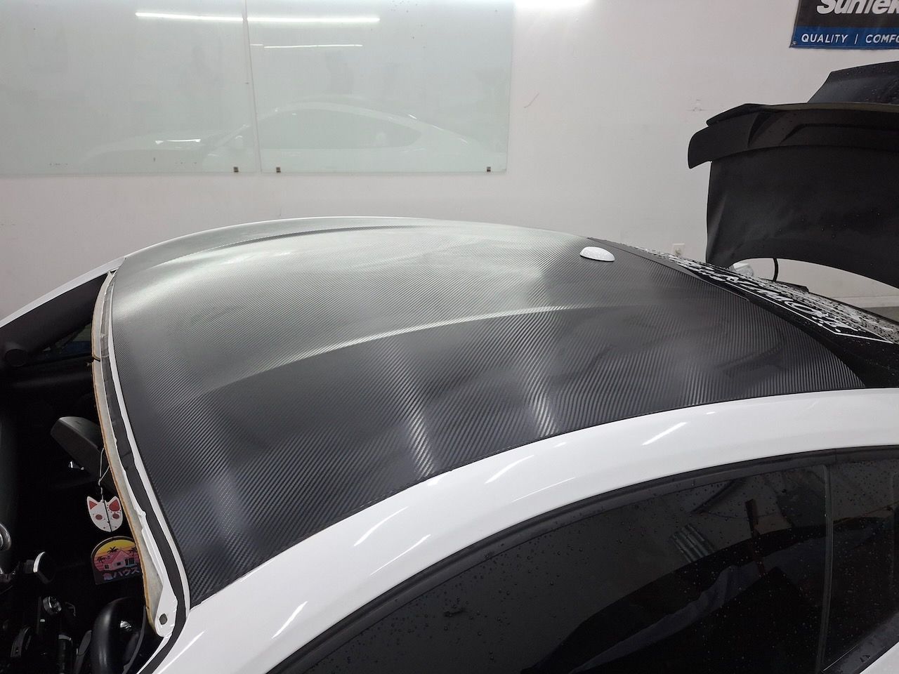 A white car with a black roof in a garage