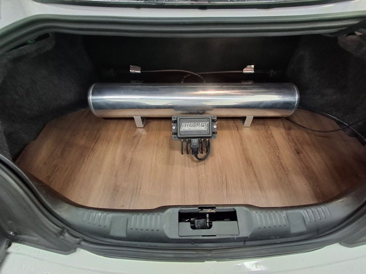 The trunk of a car with a wooden floor and air suspension.