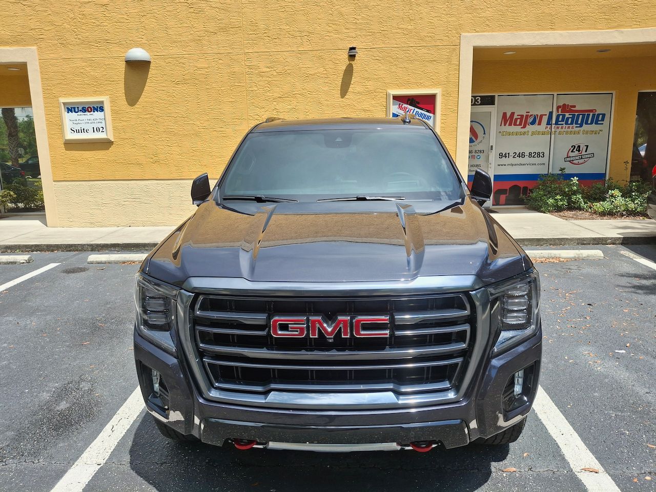 A gmc truck is parked in a parking lot in front of a building