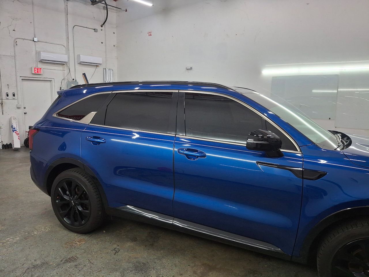 A blue suv with black wheels is parked in a garage.