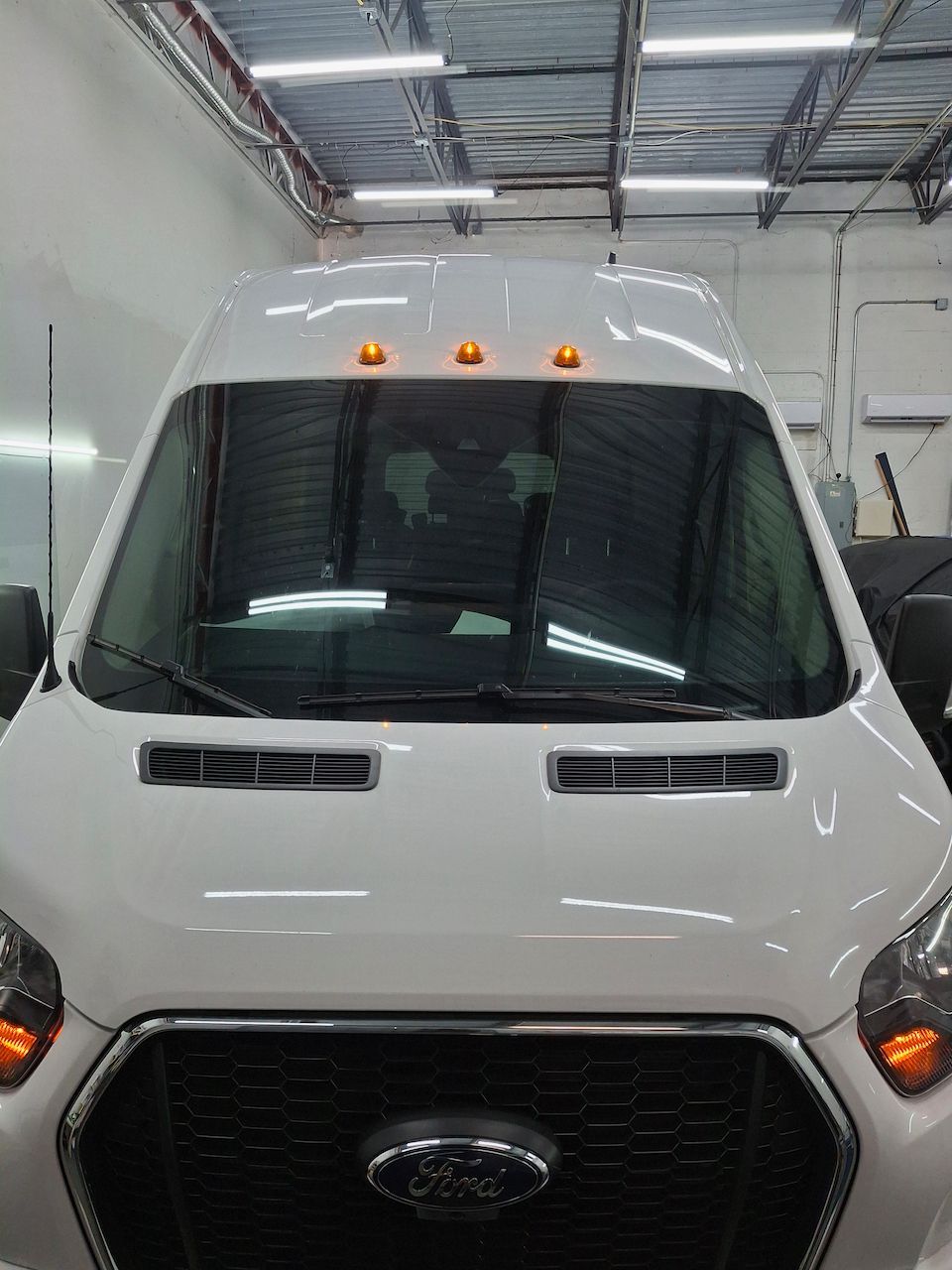 A white ford transit van is parked in a garage.