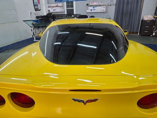 A yellow corvette is parked in a garage