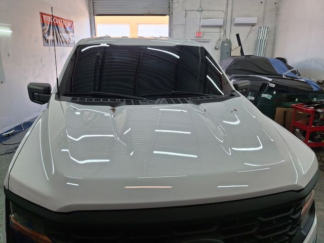 A white truck with a black grille is parked in a garage.