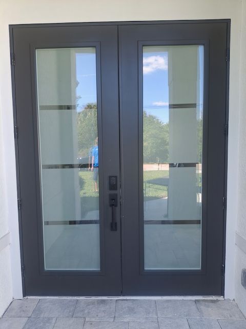 A pair of french doors with a reflection of trees in the glass.