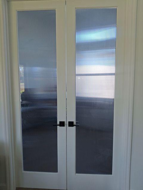 A pair of glass doors with black handles in a room.