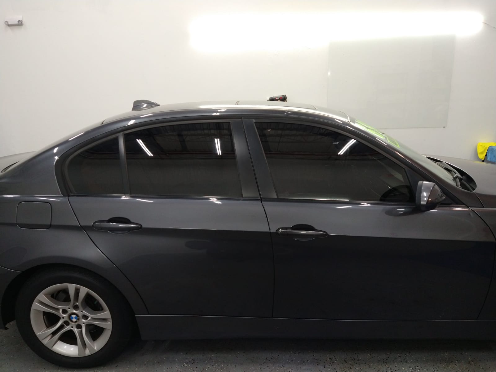 A gray car is parked in a garage next to a white wall.