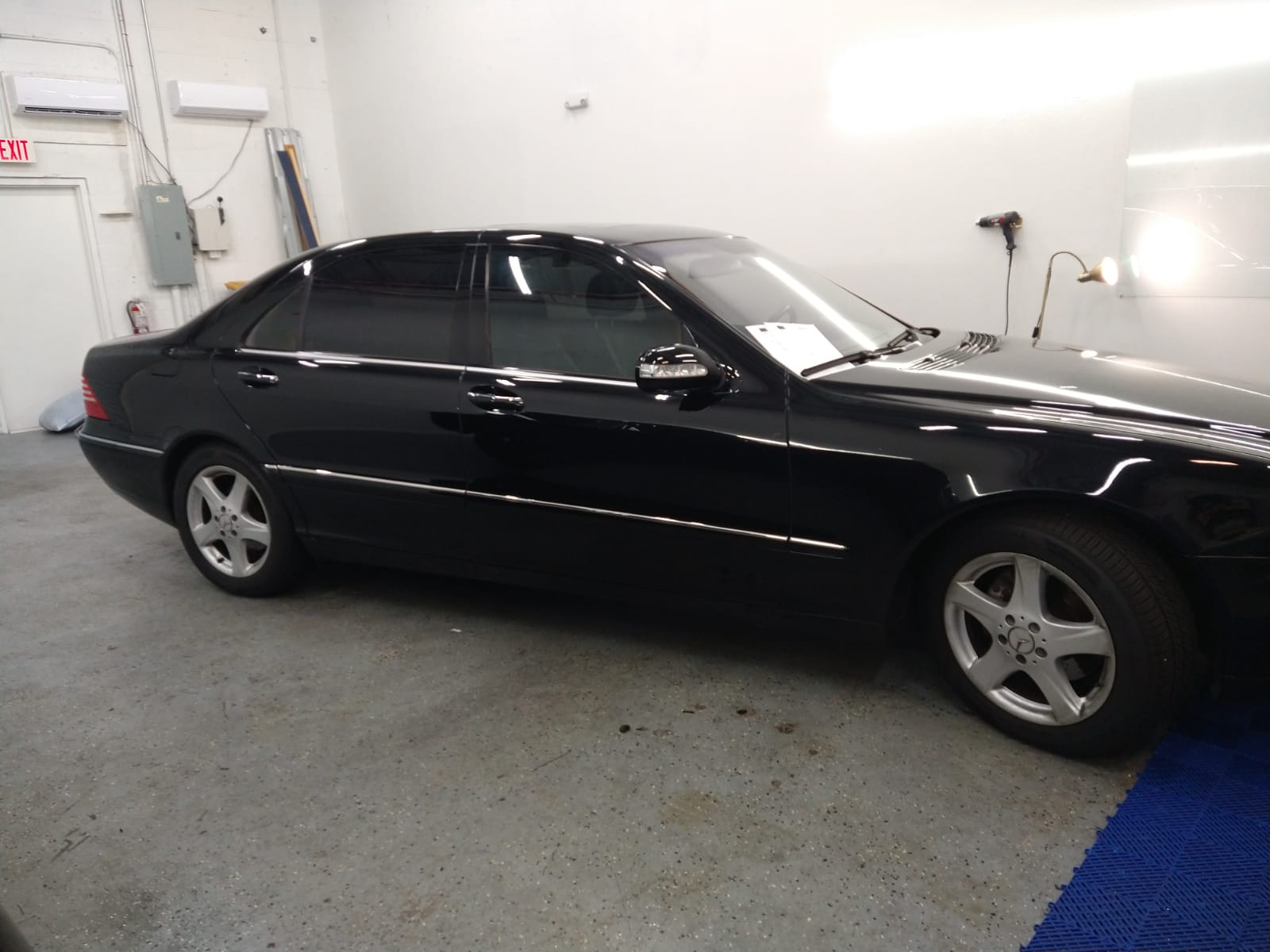 A black car with silver wheels is parked in a garage