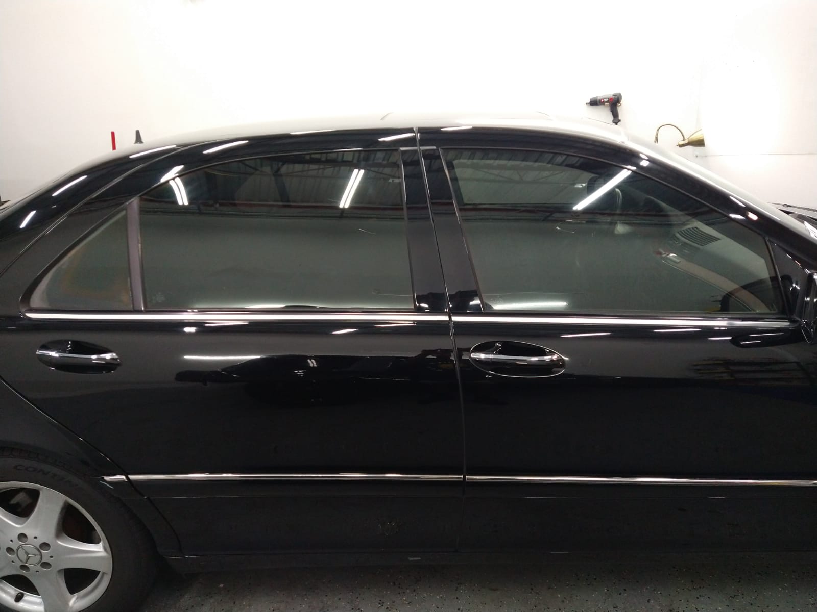 A black car with tinted windows is parked in a garage.