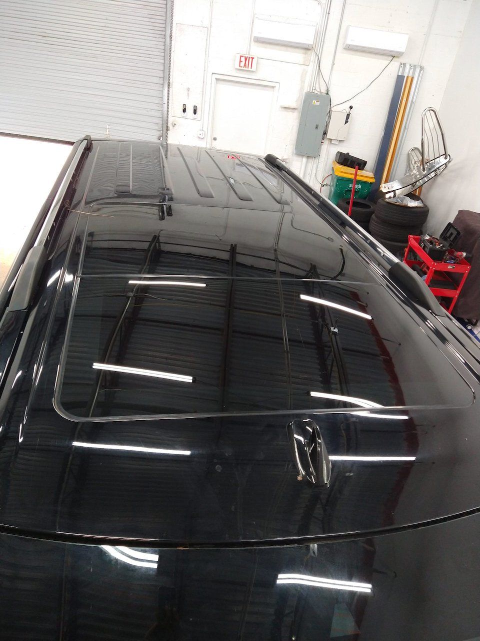 A black car with a sunroof is parked in a garage.