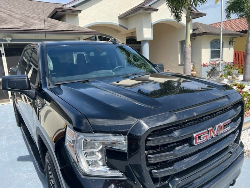 A black gmc truck is parked in front of a house.