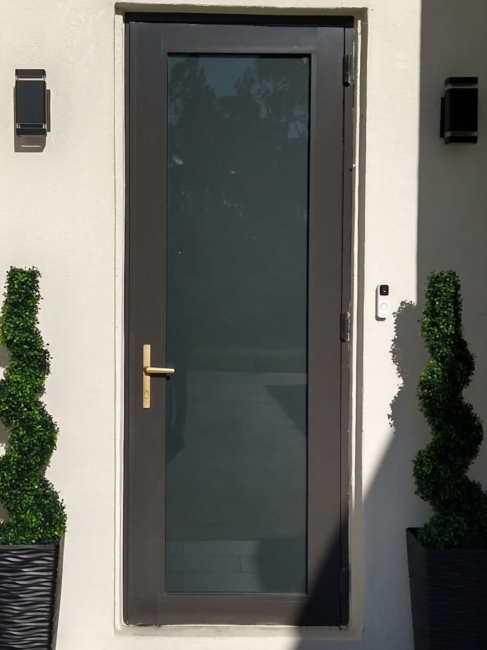 A black door with a brass handle on a white wall