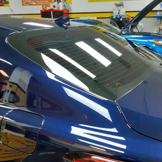 A blue car is parked in a garage with the hood open