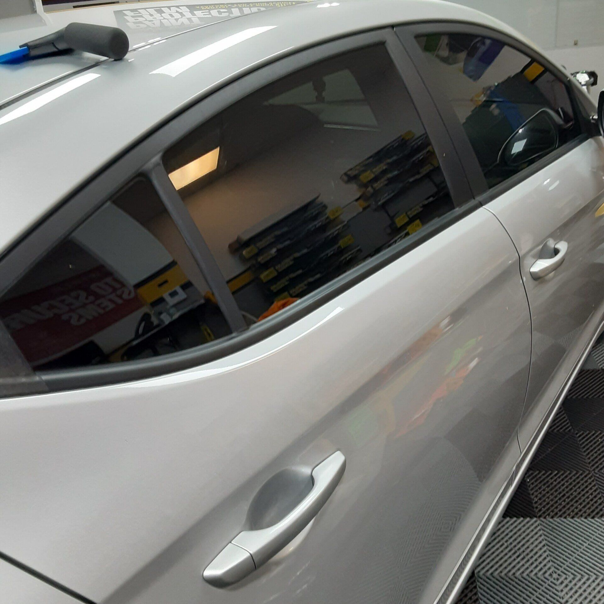 A silver car is parked on a checkered floor in a garage.