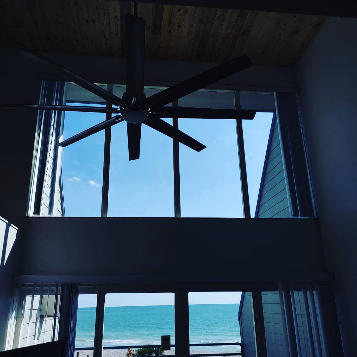 A room with a ceiling fan and a view of the ocean