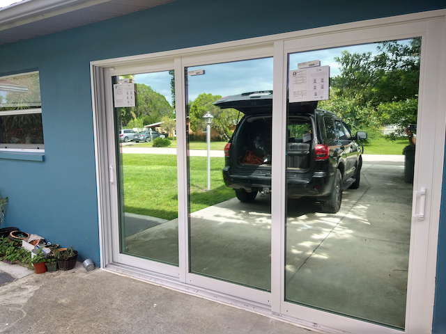 A car is parked in front of a sliding glass door.