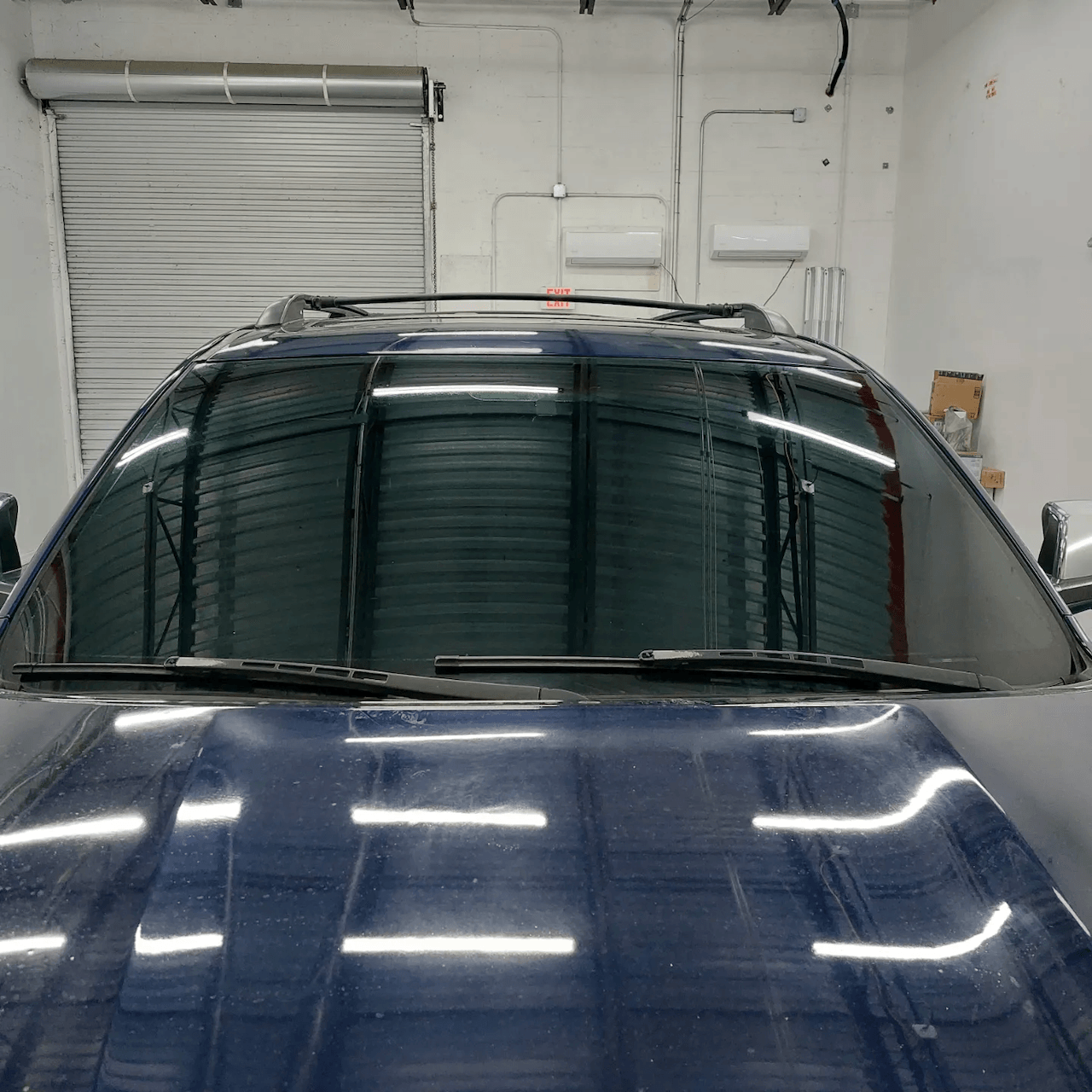 A blue suv is parked in a garage with the hood up
