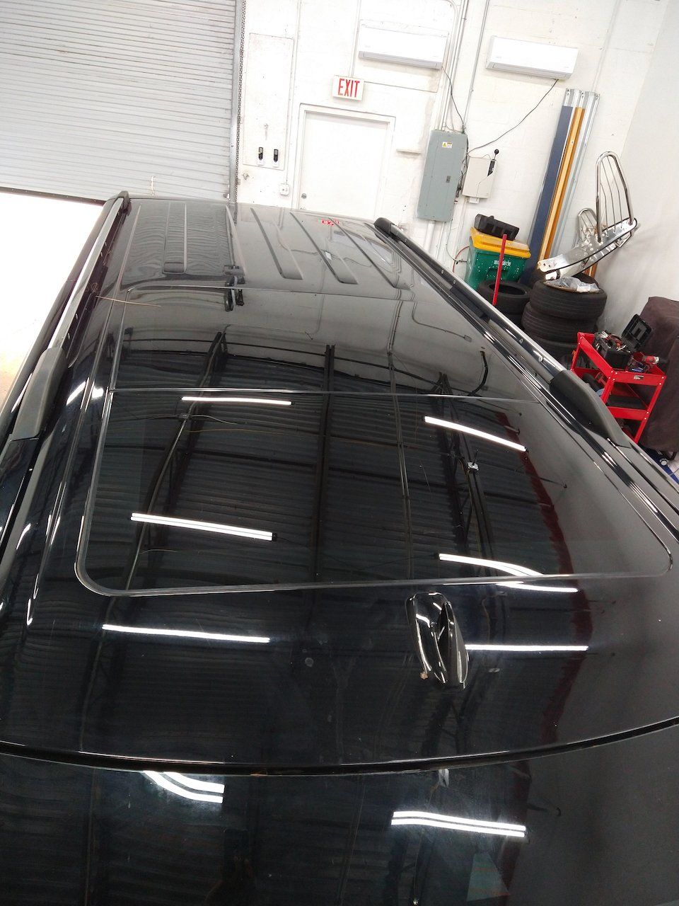 A black car with a sunroof is parked in a garage.