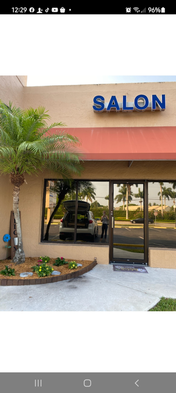 A picture of a salon with a car parked in front of it.