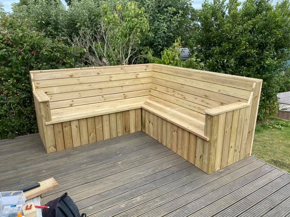 A wooden bench is sitting on top of a wooden deck.