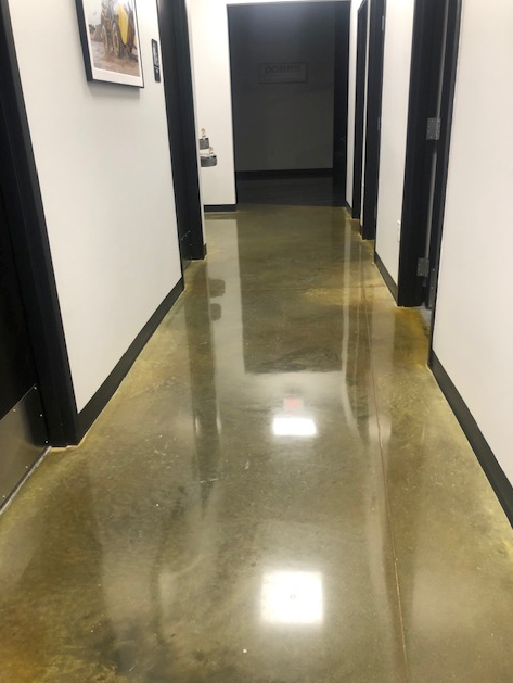 A hallway with a shiny concrete floor and a picture on the wall