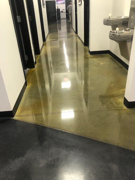 A hallway with a shiny concrete floor and two sinks