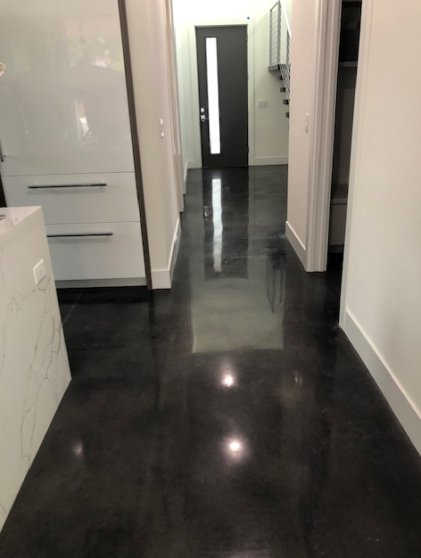 A hallway with a black floor and a white door