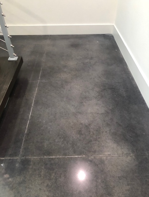 A black tile floor in a room next to a staircase.