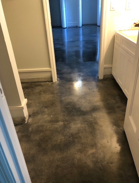A hallway with a concrete floor and a sink in a house.