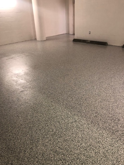 A large empty room with a gray floor and white walls.