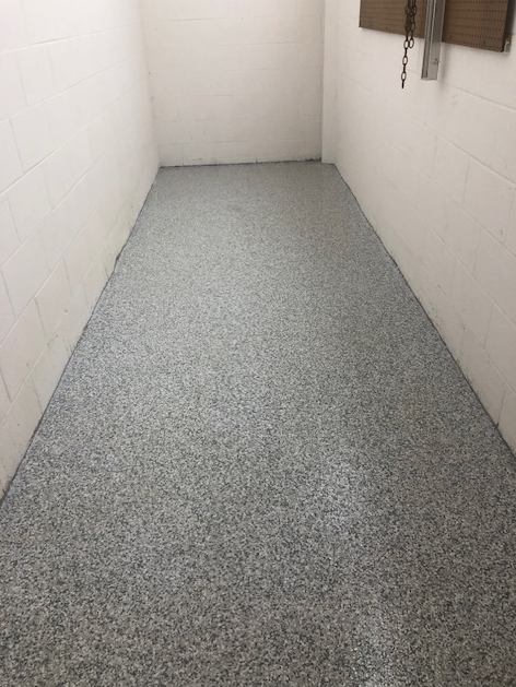 A narrow room with a gray floor and white walls.