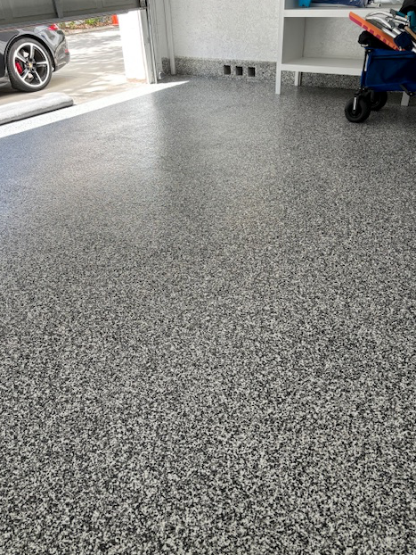 A garage floor with a car parked in the background.