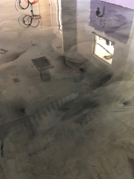 A concrete floor with a reflection of a building in it.