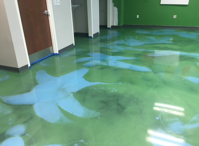 A green and blue floor in a room with a door.
