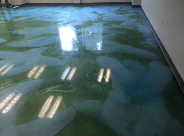 A blue and green floor with a reflection of lights on it.