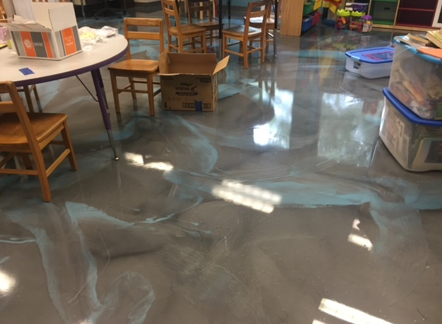 A classroom with a table and chairs and a box on the floor.
