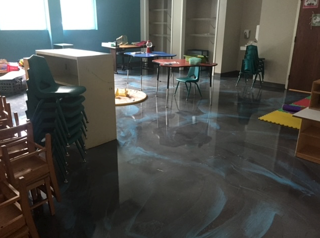 A room with tables and chairs and a stack of chairs on the floor