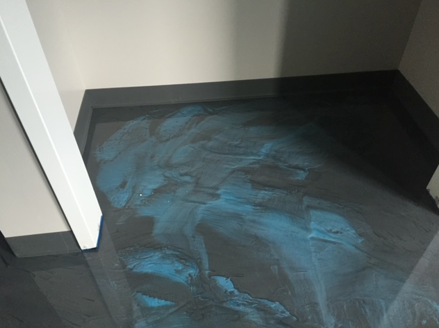 A black and blue floor in a room with a door.