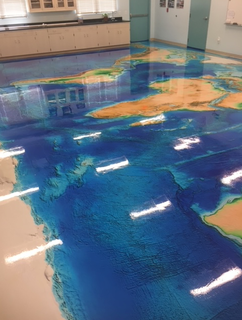 A map of the world is on the floor of a room.