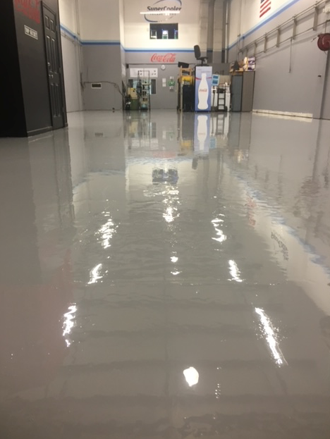A warehouse with a shiny floor and a forklift in the background.