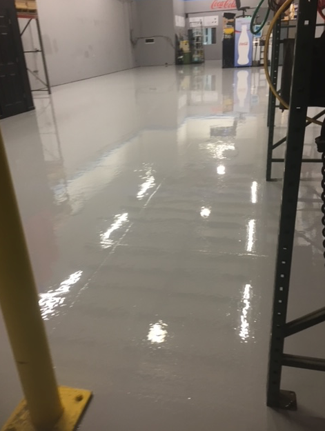 A warehouse with a shiny white floor and a yellow pole.